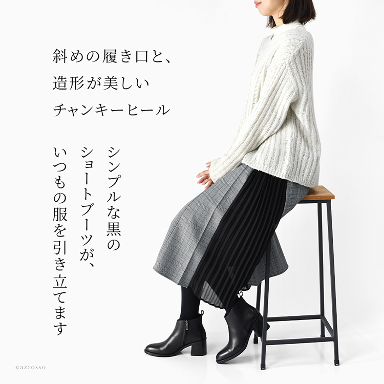 斜めの履き口と造形的な太ヒールが印象的な、黒の本革アンクルブーツを着用した女性モデル