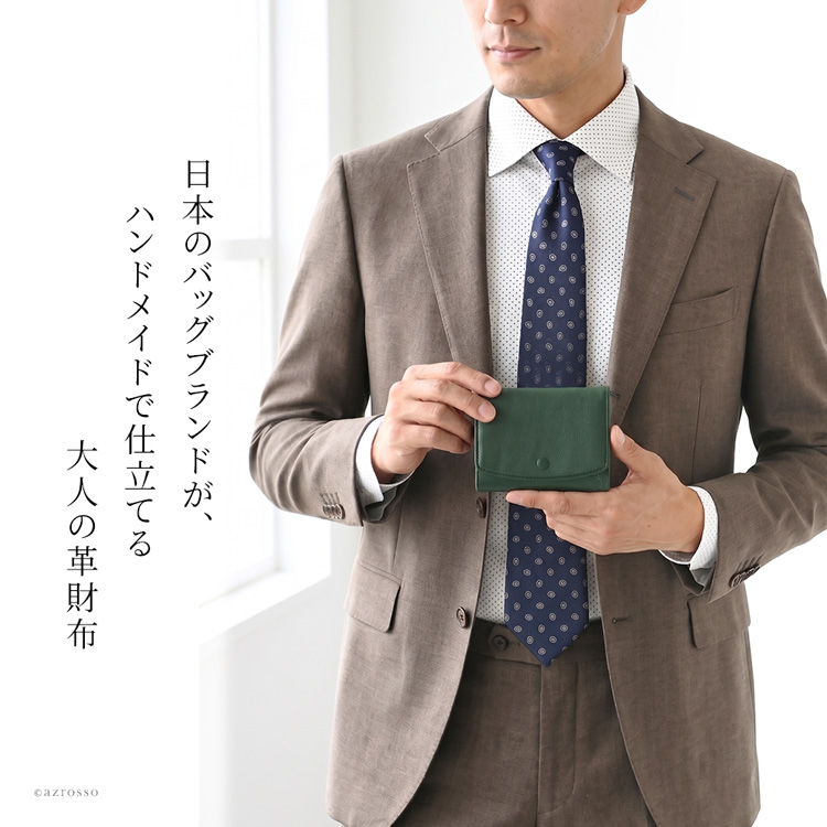 小さく持って、所作はスマートに。クルミボタンと端正なかぶせが映える日本製の本革ミニ財布を持つ大人男性