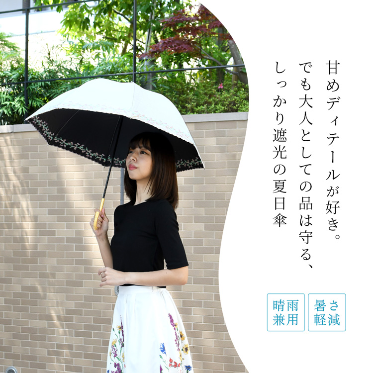 刺繍入りの晴雨兼用日傘を差す女性。UVカット100％・遮光100％で涼しく過ごせるブラックコーティング仕様。内側黒で遮熱性も高く、軽量設計で持ちやすい。