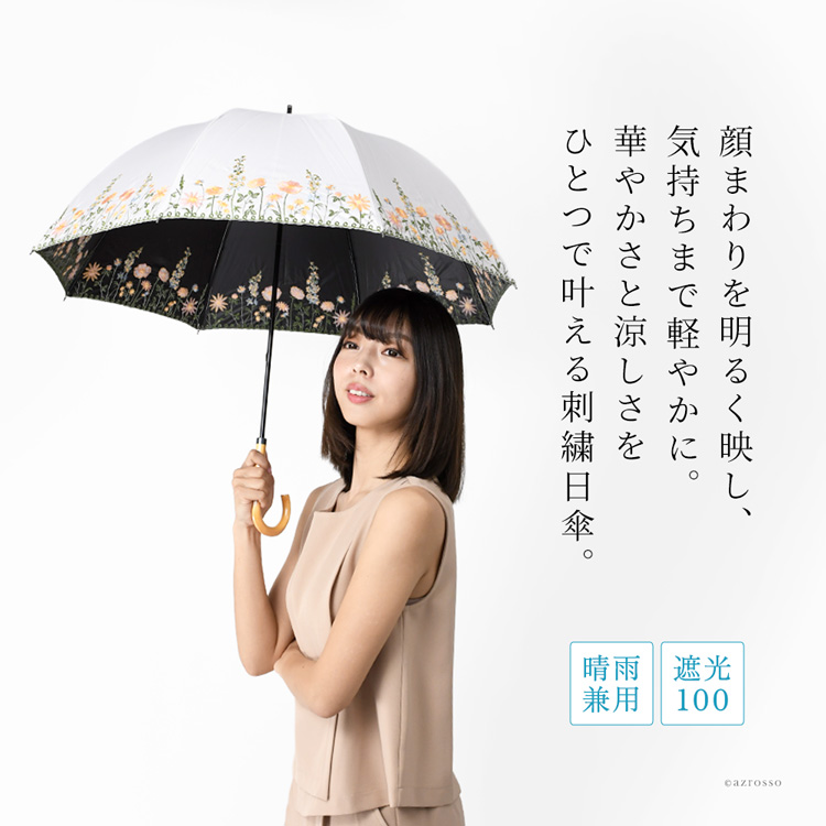刺繍入りの晴雨兼用日傘を差す女性。UVカット100％・遮光100％で涼しく過ごせるブラックコーティング仕様。内側黒で遮熱性も高く、軽量設計で持ちやすい。