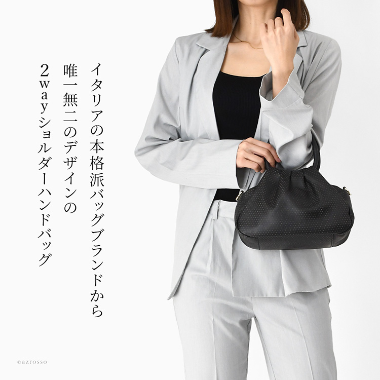 イタリア製のレザーで作られた、ショルダーバッグにもなる可愛らしいバッグをハンドバッグとして持つ、スーツの女性。